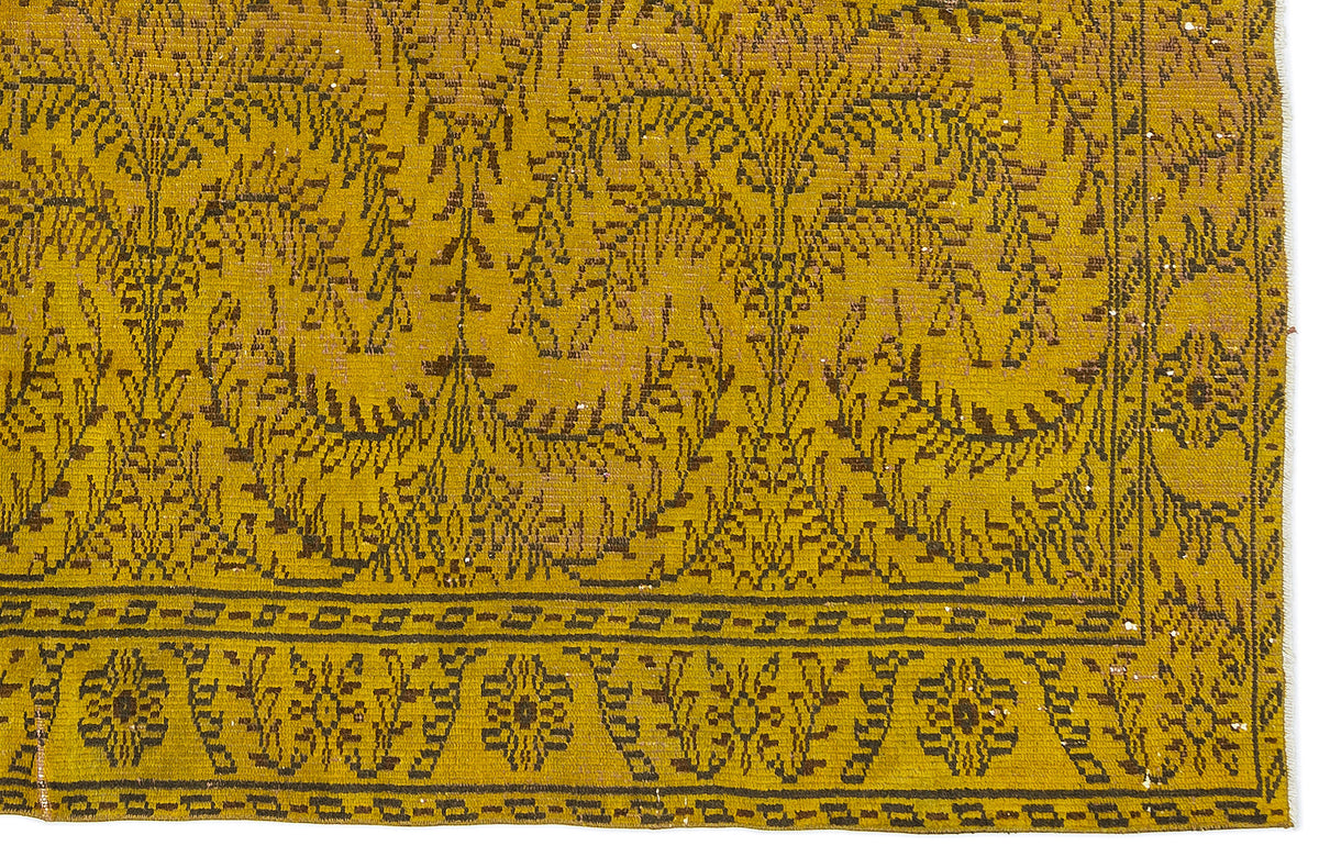 Mustard yellow rug with a dark brown botanical leaf pattern and a geometric border.