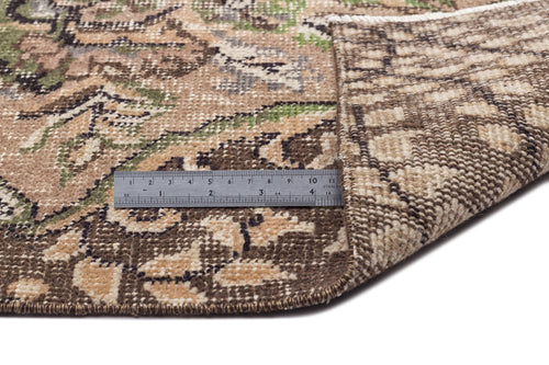Load image 1 in gallery view. Brown, beige, and green floral patterned rug with a folded corner revealing the woven backing and a metal ruler for scale.