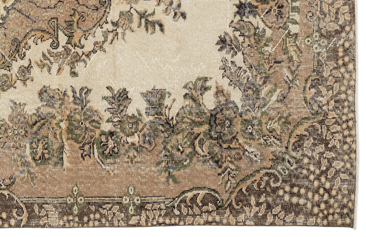 Distressed beige and brown rug with a traditional floral medallion pattern and green accents.