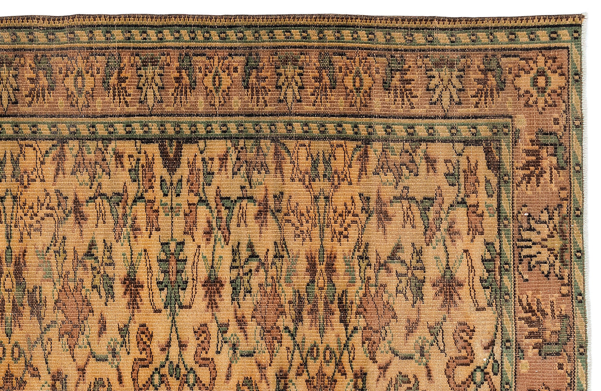 Tan and sage green traditional rug with a geometric floral border and an abstract, distressed botanical pattern.