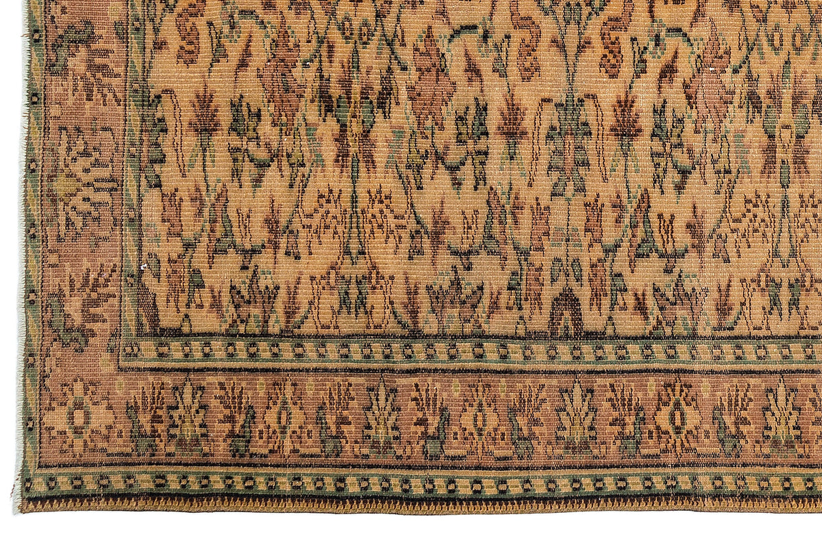 Tan, brown, and sage green traditional rug with a repeating floral motif and a decorative geometric border.