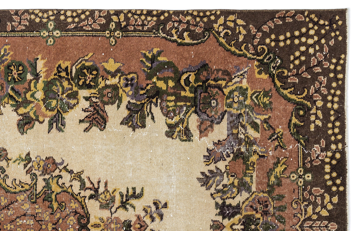 Distressed traditional rug with a floral border in brown, cream, green, and yellow on a white background.