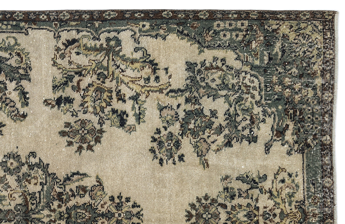 Beige rug with a distressed floral medallion pattern in muted green, brown, and charcoal on a white background.