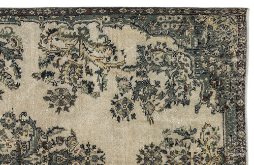 Load image 1 in gallery view. Beige rug with a distressed floral medallion pattern in muted green, brown, and charcoal on a white background.