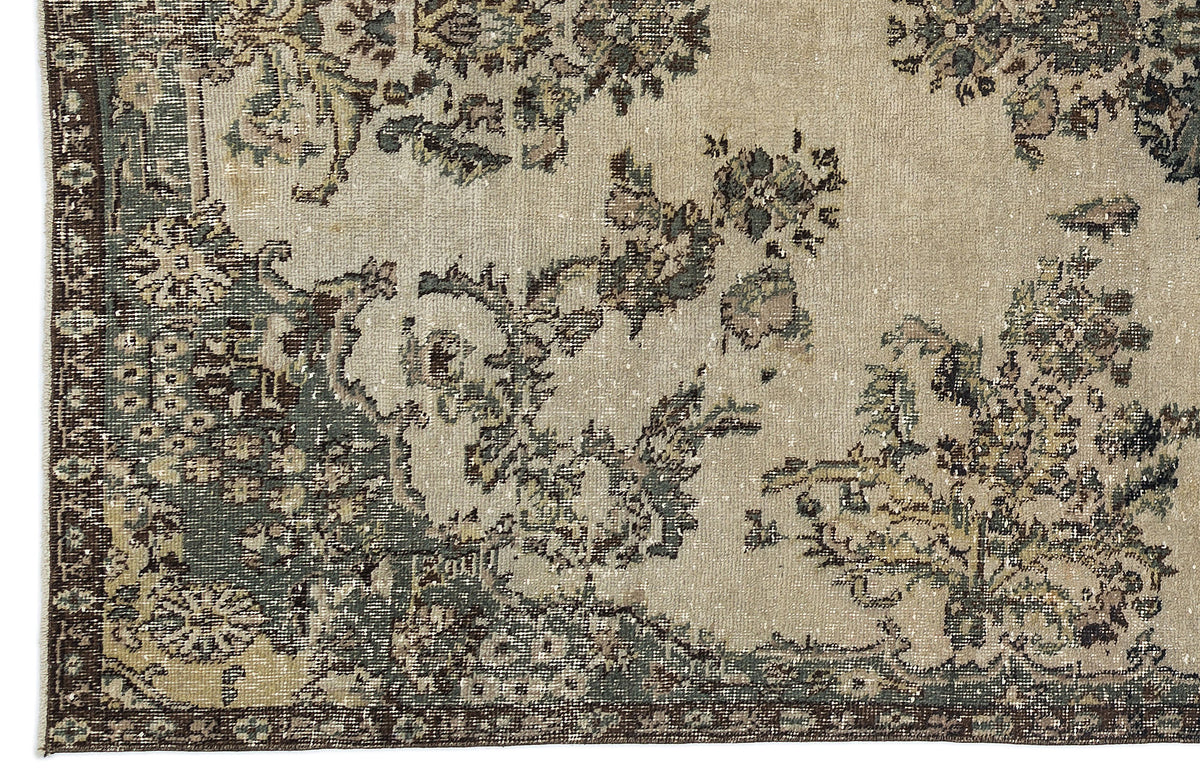 Beige and sage green vintage-style rug with a distressed floral medallion pattern and a dark border.