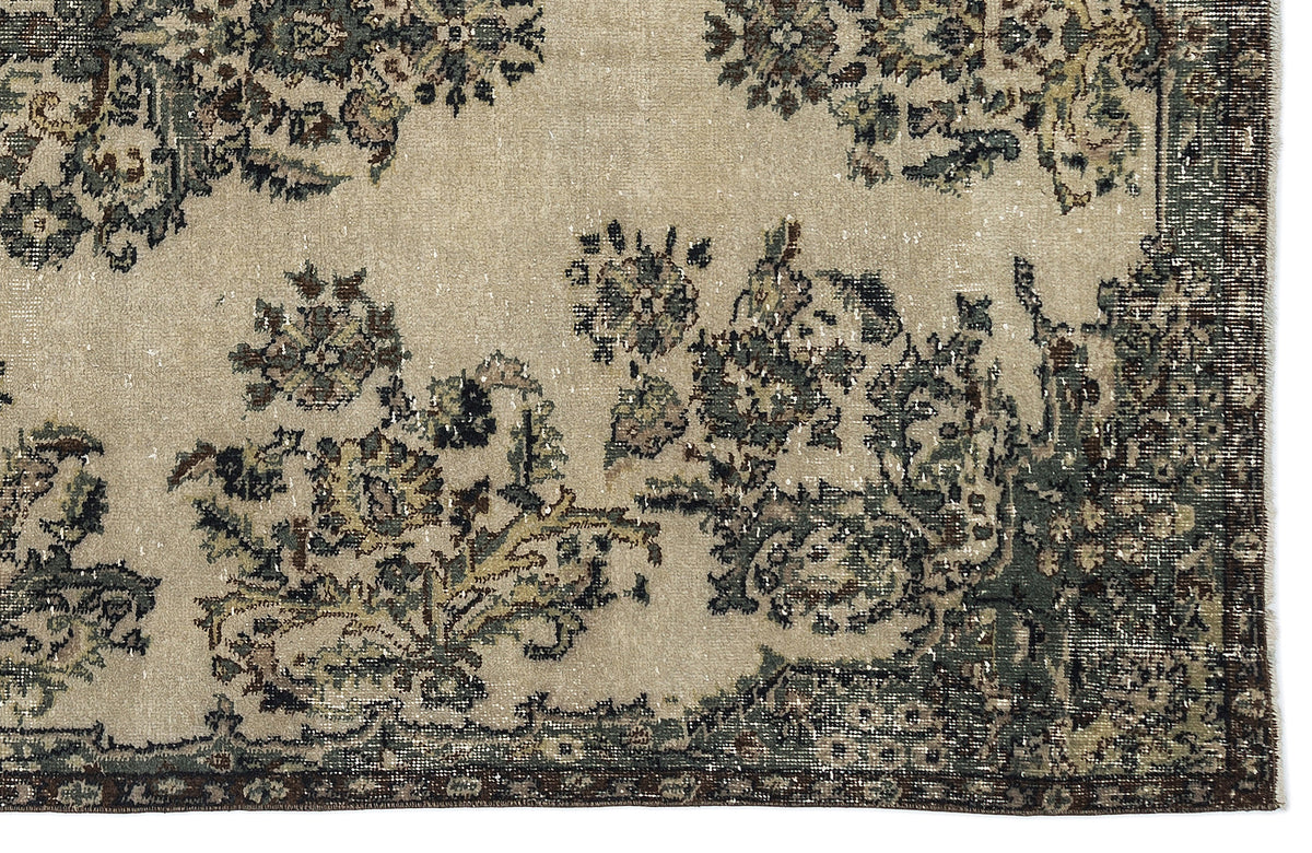 Beige rug with a distressed floral pattern in muted green, brown, and charcoal tones.