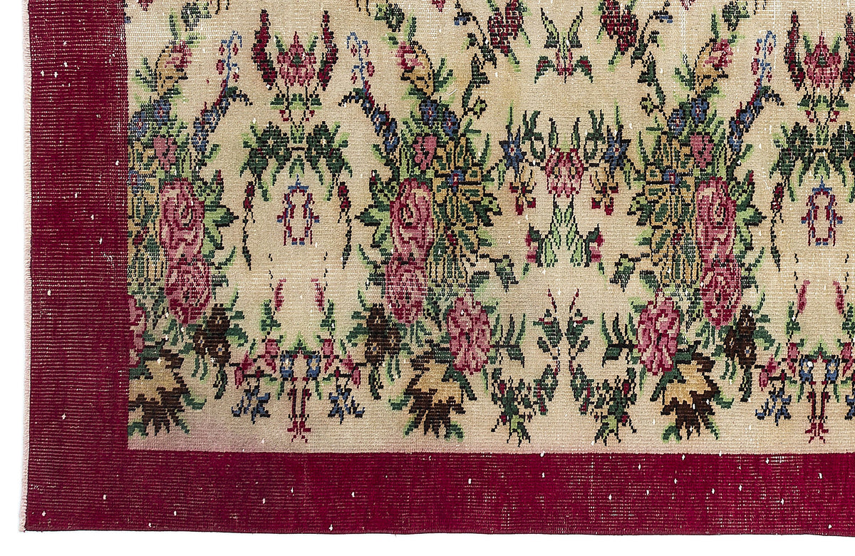 Beige rug with a floral pattern in red, green, and blue, featuring a wide solid red border.