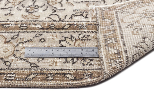 Load image 1 in gallery view. Beige and brown distressed rug with a traditional floral pattern, shown with a metal ruler for scale on a white background.
