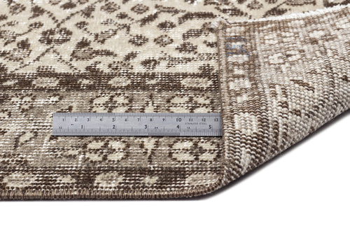Load image 1 in gallery view. Brown and beige floral patterned rug with a folded corner showing the woven backing and a metal ruler for scale.