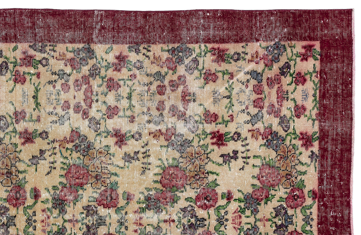Distressed beige rug with a floral pattern in red, green, and blue, featuring a wide dark red border.