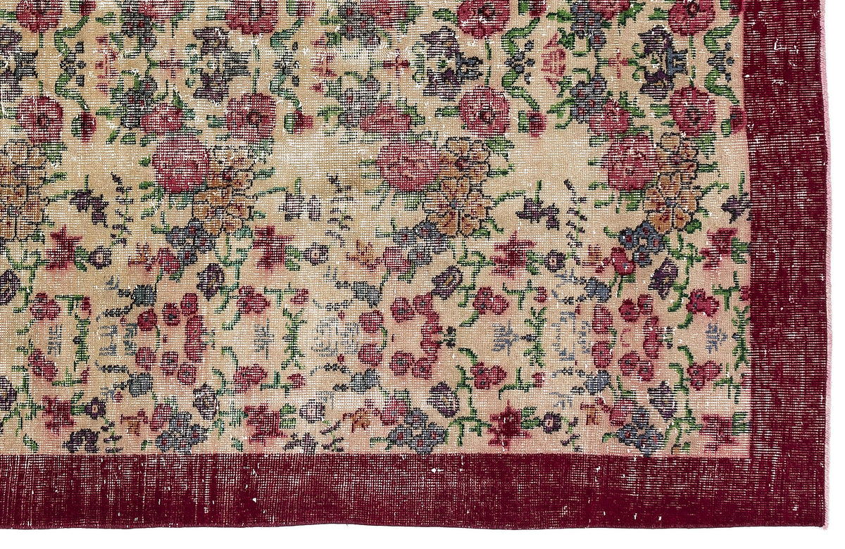 Beige vintage-style rug with a distressed floral pattern in red, green, and blue, featuring a solid dark red border.