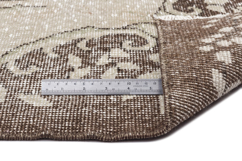Load image 1 in gallery view. Brown and beige distressed medallion rug with a metal ruler showing pile texture and weave detail.
