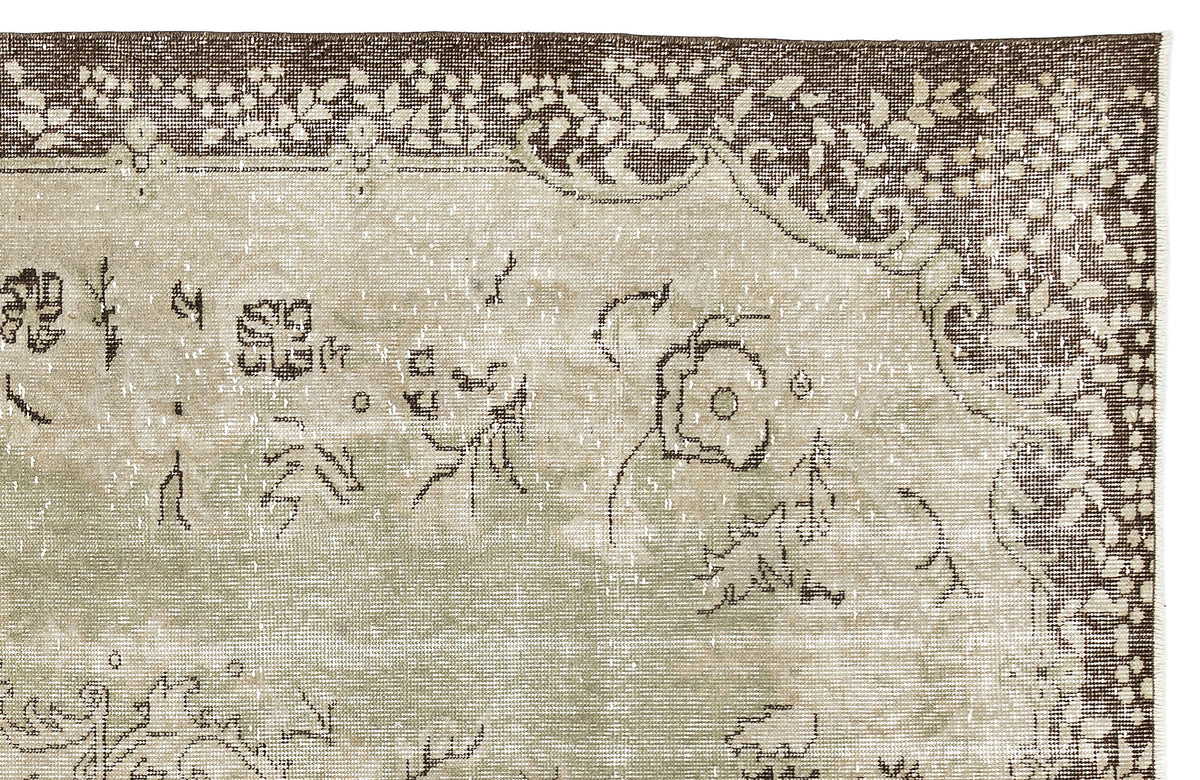 Distressed sage green and brown rug with a faded floral medallion pattern and ornate border on a white background.