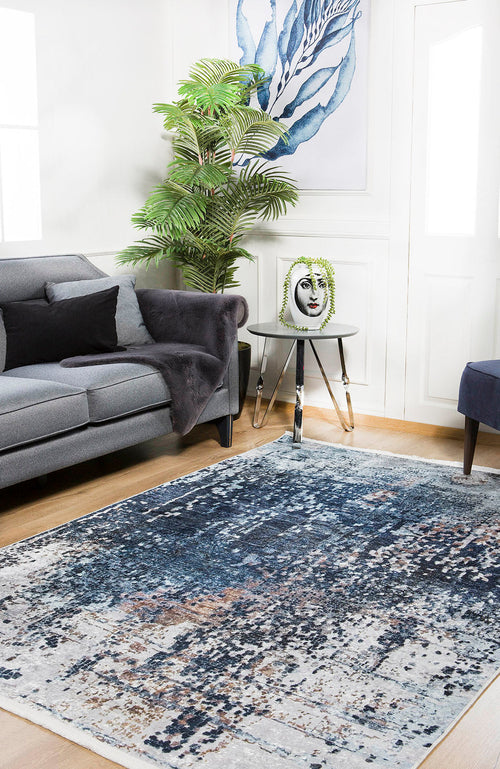 Load image 1 in gallery view. A modern living room with a gray sofa, black pillow, potted plant, round side table with a decorative face vase, abstract blue wall art, and the Abstract Atmosphere - Washable Rug - JR834 (Custom Size), ideal for high-traffic areas.