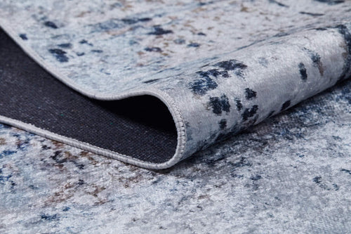Load image 1 in gallery view. A close-up of the Abstract Atmosphere - Washable Rug - JR834 (Custom Size) in soft blue, gray, and beige tones. One corner is folded to show its dark textured underside—washable and ideal for high-traffic spaces.