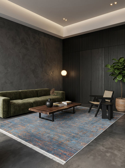 Load image 1 in gallery view. Blue and copper distressed area rug with fringe, styled in a modern living room with a green velvet sofa.