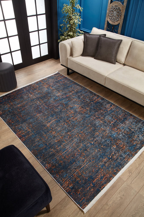 Load image 1 in gallery view. A modern living room features a beige sofa, dark cushions, wooden floor, a plant, blue walls with molding and art, and the Abstract Harmony - Machine-Washable Rug JR1882 (Custom Size) in blue and orange—ideal for high-traffic areas.