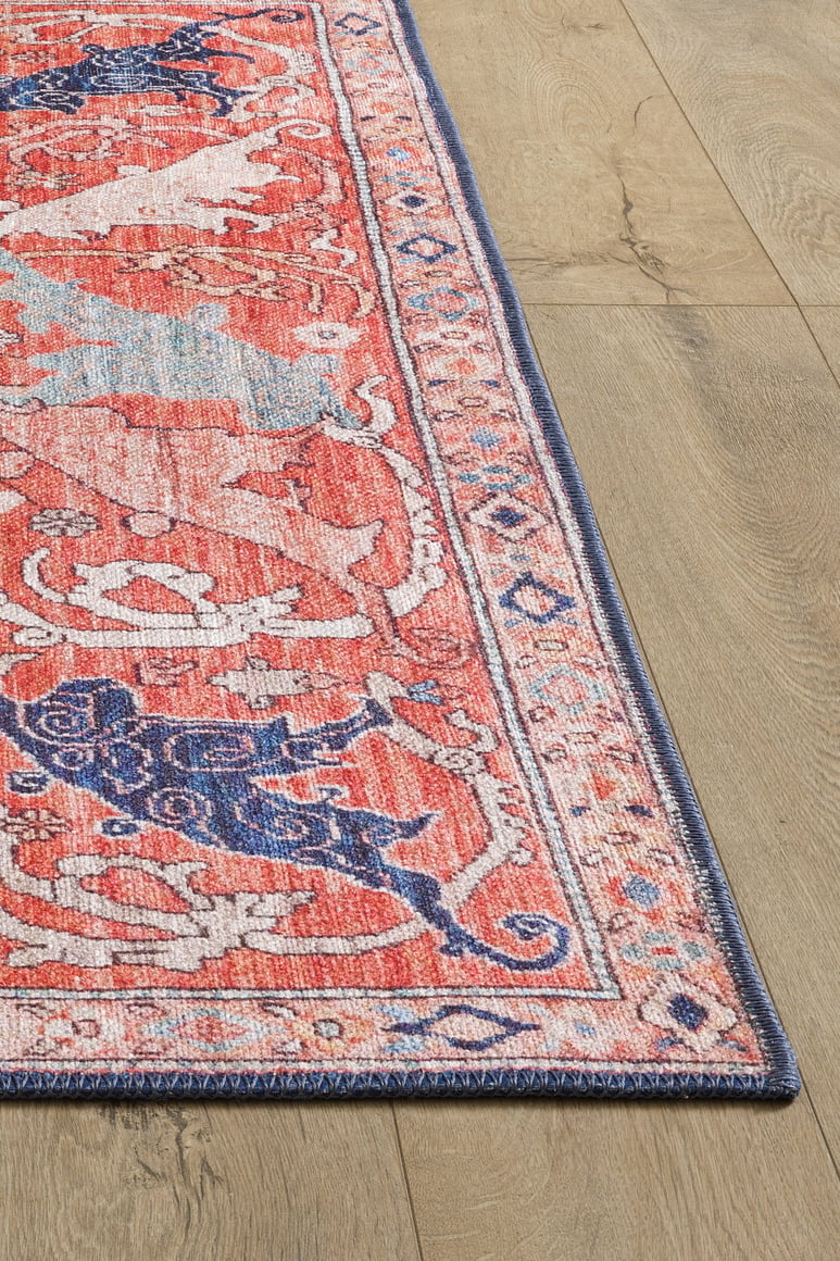 A close-up of the Aegis Handmade-Design Washable Rug - LCC3029, featuring pink and blue patterns with a detailed border on a light wood floor. Its vibrant colors and flat weave make it ideal for high-traffic areas.
