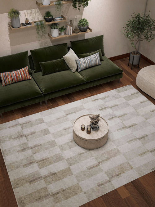 Load image 1 in gallery view. A modern living room featuring a green velvet sofa, patterned pillows, a round beige coffee table with decor, wooden floors, wall shelves with plants, potted plants in the corners, and an Aged Elegance - Washable Rug - JRN37 (Custom Size).