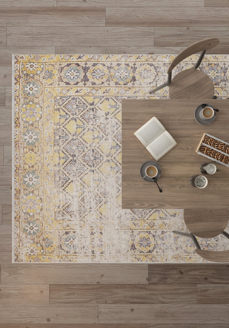 Overhead view of the Aged Splendor - Washable Rug - JR1906 (Custom Size) under a wooden table set with coffee, an open book, and snacks, with two chairs nearby—ideal for high-traffic areas.