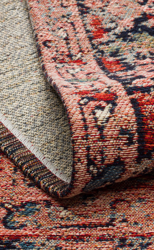 Load image 1 in gallery view. A close-up of the Anatolian Weave - Washable Kilims - AND01 shows its red, blue, and beige flatwoven patterns, partially lifted to reveal the textured underside and edges with detailed, colorful traditional motifs.