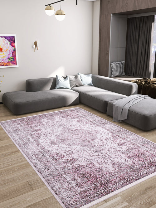 Load image 1 in gallery view. A modern living room with a large gray sectional sofa, two blue pillows, a gray throw blanket, wooden floors, wall art, a gold wall sconce, a contemporary ceiling light, and the Ancient Emblem - Washable Rug - JR200 ideal for high-traffic areas.