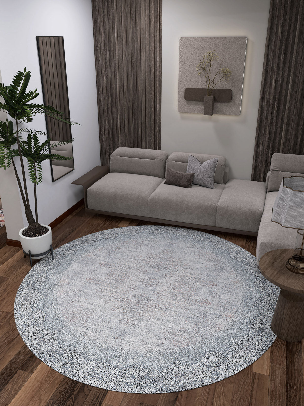 A modern living room features a gray sectional sofa, the Ancient Treasure - Washable Rug - JR1785 (Custom Size) in blue—ideal for high-traffic areas—a potted plant, wood panel walls, a small side table, and minimalist wall art above the couch.