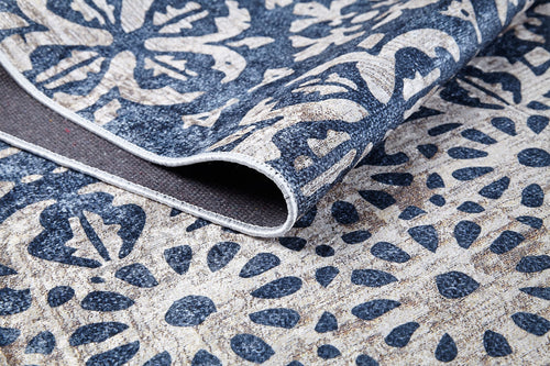 Load image 1 in gallery view. A close-up of the Antique Flourish - Washable Rug - JR1591 shows its blue base with beige floral and geometric designs. A folded corner displays the durable, washable fabric—ideal for high-traffic areas and easy to maintain.