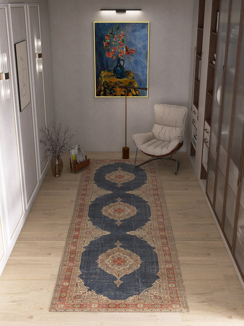 Load image 1 in gallery view. A modern hallway with a light wood floor, a white lounge chair, a vase with branches, and the Antique Symphony - Washable Rug - JRN1017 featuring a subtle medallion design. A floral painting in a blue vase hangs above the chair under a picture light.