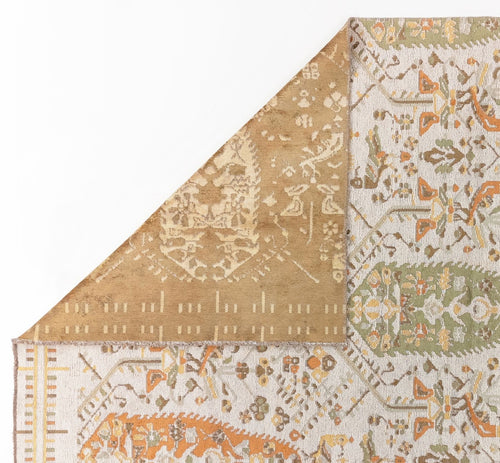 Load image 1 in gallery view. The Saffron Heritage Area Rug APX1912 displays intricate white, orange, green, and gold motifs on a light background, with a folded corner showing its tan and beige underside.