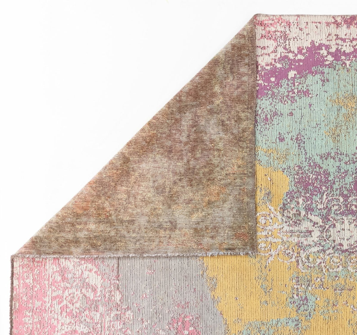 Abstract rug with a folded corner showing a brown textured backing and a multi-colored, distressed floral pattern.