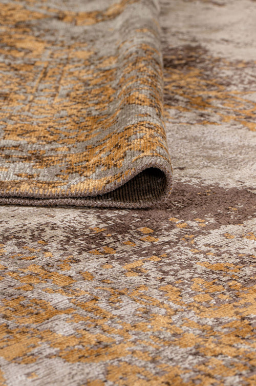 Load image 1 in gallery view. A close-up of the Golden Fade Area Rug APX1922 shows its textured, flatwoven surface with a folded corner, featuring abstract and geometric patterns in beige, brown, and gold shades.
