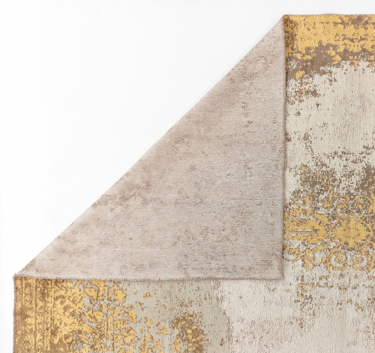The Golden Fade Area Rug APX1922 features a beige, yellow, and gray pattern with one corner flipped to show its plain light beige underside against a white background.