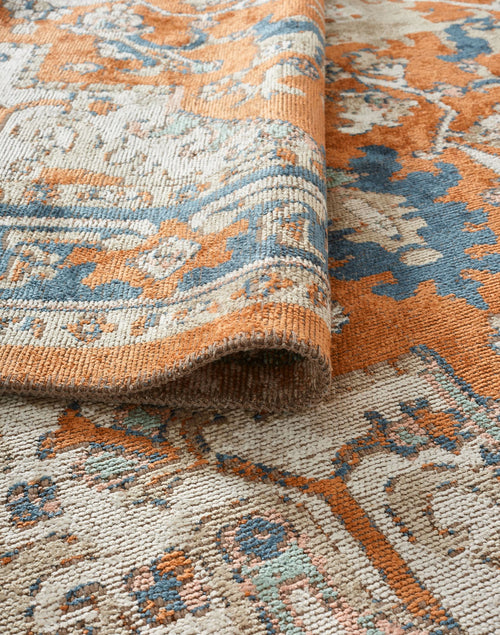 Load image 1 in gallery view. Distressed orange, blue, and cream rug with a traditional floral medallion pattern, shown folded to reveal the texture.