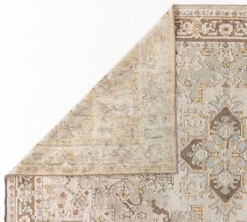 Load image 1 in gallery view. A close-up of a corner of the Ivory Medallion Area Rug APX1932, showing intricate floral and geometric patterns in beige, brown, and blue tones, with one corner folded to display the lighter underside.