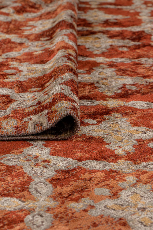 Load image 1 in gallery view. Rust, grey, and gold distressed rug with an abstract medallion pattern, shown with a corner folded over.