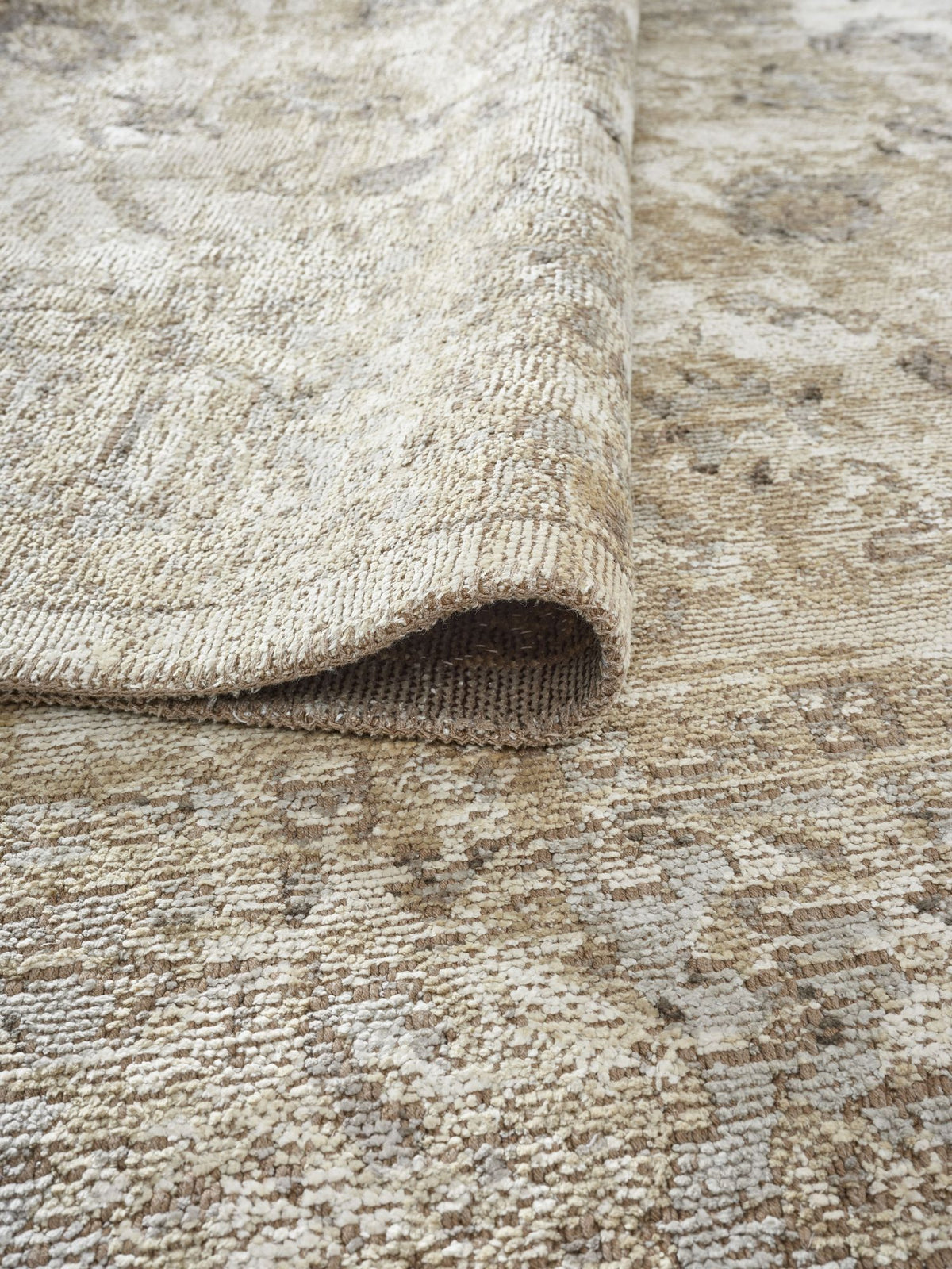 A close-up of the Stone Garden Area Rug APX1961, slightly folded at one corner, highlights its textured weave and subtle color variations for a vintage-inspired look.