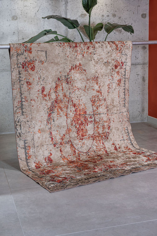 Load image 1 in gallery view. Beige and rust-red distressed medallion rug draped over a metal bar against a concrete wall.
