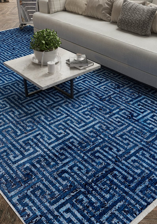 Load image 1 in gallery view. A modern living room features a white sofa, gray and white cushions, a marble coffee table with a plant and tray, and the Art Deco Elegance - Washable Rug - JR1224 (Custom Size) in blue geometric pattern on the wooden floor.