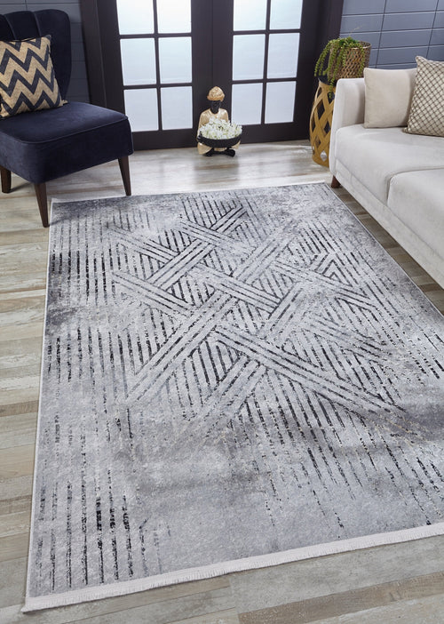 Load image 1 in gallery view. A living room features the Art Deco Empress - Washable Rug - JR1867 (Custom Size), a modern light gray-anthracite geometric rug, paired with a white sofa, dark blue chevron pillow chair, decorative basket, and large black-framed windows.