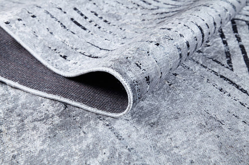 Load image 1 in gallery view. A close-up of the Art Deco Empress - Washable Rug - JR1867 (Custom Size) in gray and anthracite, featuring a subtle abstract black-and-white pattern. A folded corner reveals the dark backing—perfect for sophisticated spaces.