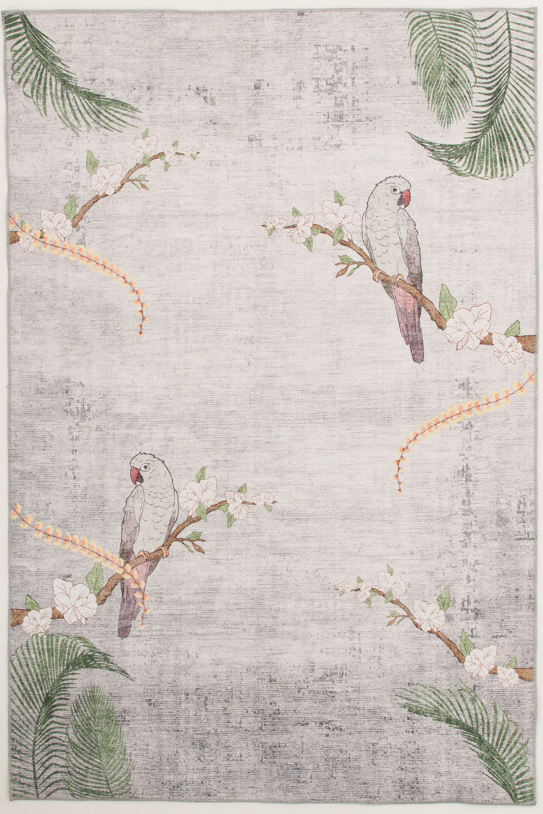 The Ashwing Silence - Washable Rug (JR0048) features two gray parrots with pink faces on flowering branches, green palm leaves, and orange floral vines in the corners. Its light-colored background has a subtle, textured look.
