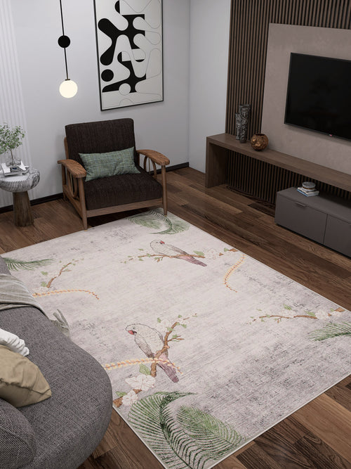 Load image 1 in gallery view. A modern living room with dark wooden floors, a gray sofa, a wooden armchair, a wall-mounted TV, abstract wall art, and the Ashwing Silence - Washable Rug - JR0048 featuring birds and leaves.