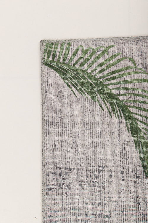 Load image 1 in gallery view. A green palm leaf print accents the upper left corner of the Ashwing Silence - Washable Rug - JR0048, featuring a textured, light-colored surface set against a plain light background.