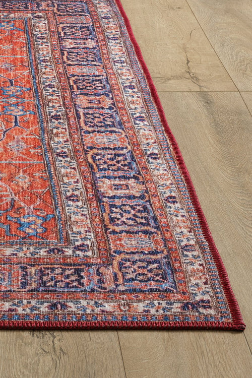 Load image 1 in gallery view. A close-up of the Aurelius Coral Washable Rug - LCC3005 (Custom Size), featuring vibrant red, purple, and blue geometric patterns—ideal for allergy-sensitive homes and high-traffic areas—shown on a light wood floor.