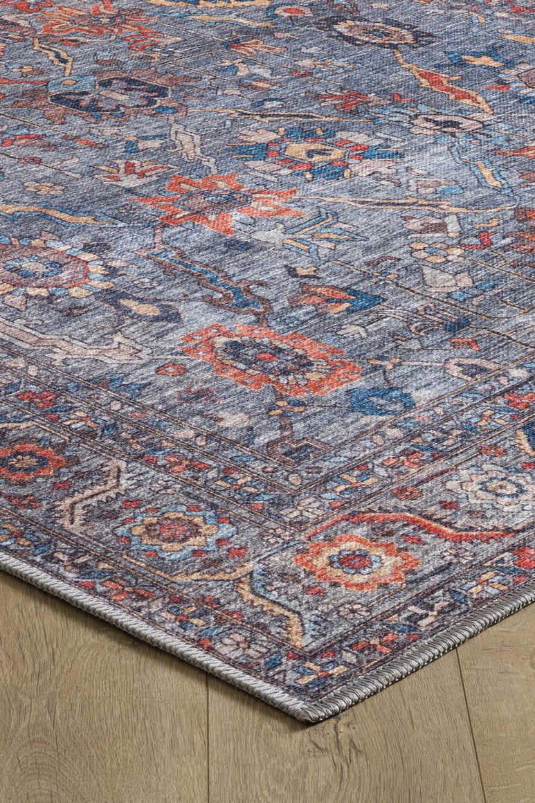 A close-up of the Bellaris Gray Washable Rug - LCC3003 (Outlet) US, featuring intricate red, blue, and orange floral patterns on a gray background, is shown placed on a light wooden floor.