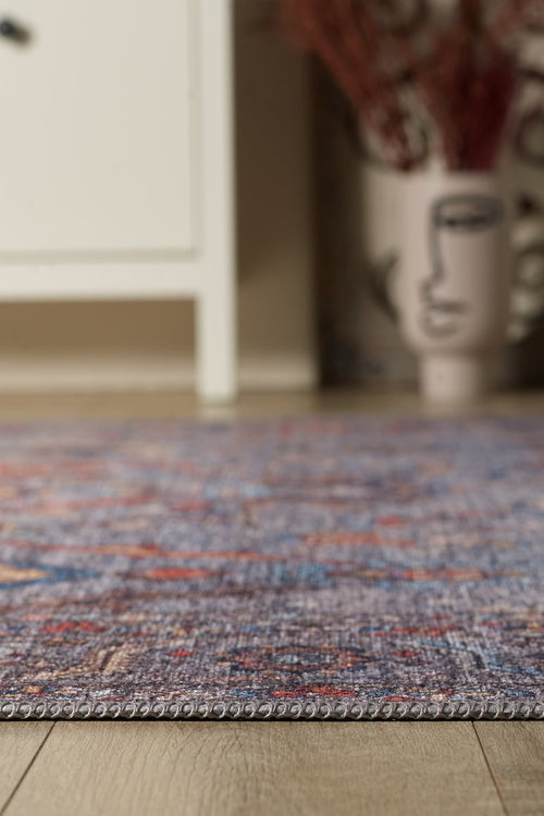 Load image 1 in gallery view. A close-up of the Bellaris Gray Washable Rug - LCC3003 (Outlet) US on a wooden floor, with a white cabinet and a decorative vase with an abstract face design blurred in the background.