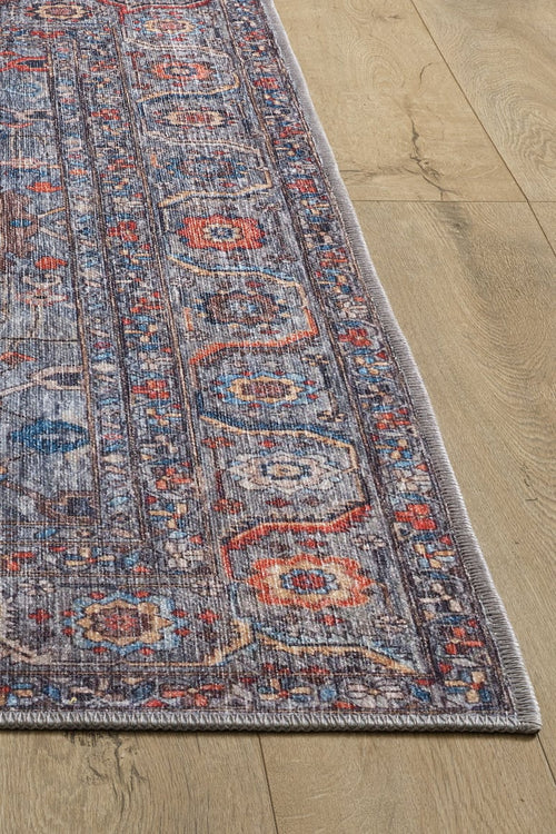 Load image 1 in gallery view. A close-up of the Bellaris Gray Washable Rug - LCC3003 (Custom Size), featuring a rectangular shape with multicolored geometric and floral patterns in blue, red, and beige, displayed on a light wooden floor.