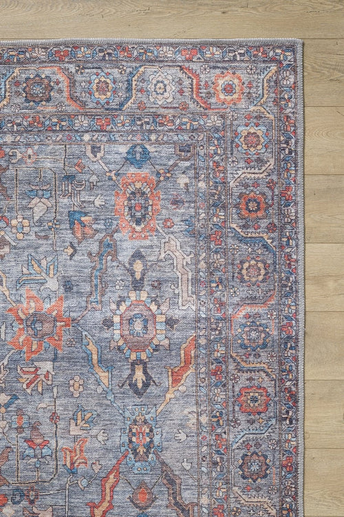 Load image 1 in gallery view. A close-up of the Bellaris Gray Washable Rug - LCC3003 (Custom Size), featuring vibrant geometric and floral patterns in blue, red, orange, and beige tones, displayed on light wooden flooring.