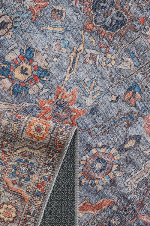 Load image 1 in gallery view. A close-up of the Bellaris Gray Washable Rug - LCC3003 (Custom Size) shows floral and geometric patterns in blue, orange, and beige. A folded corner reveals its textured underside; this allergy-friendly rug is both stylish and practical.